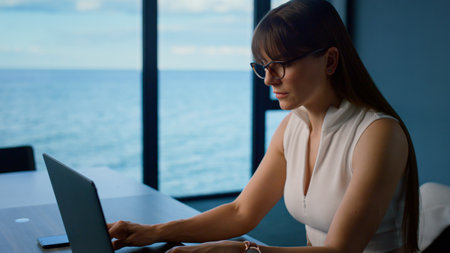 Focused manager type laptop in glass office. Closeup professional search online making financial...