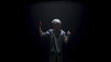 Cyber man experiencing virtual reality in dark room. Futuristic guy swiping air gesturing in studio light. Focused blonde gamer touching invisible panel in metaverse. Player immerse explore simulationの写真素材