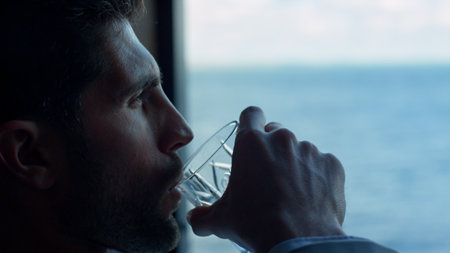Gentleman drinking whiskey ocean window view closeup. Good looking businessman tasting beverage in luxury panoramic overlooking hotel. Leader person relaxing enjoying bourbon. Successful man conceptの写真素材