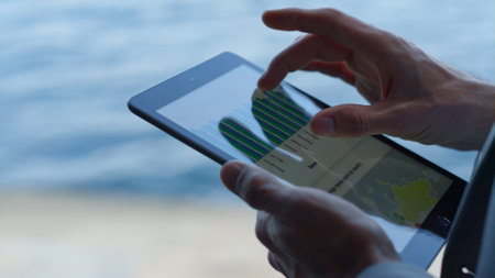Executive hands swiping tablet screen in ocean view office closeup. Unknown businessman researching analyzing charts graph using digital device in terrace. Anonymous touching tab computer aloneの写真素材