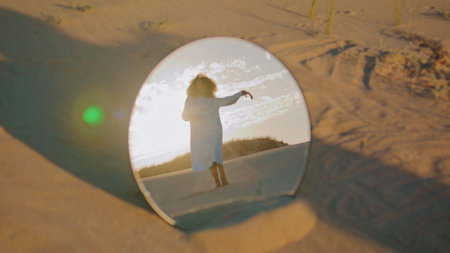 African american woman dancing at desert sunset reflecting in round mirror. Graceful young dancer performing in wilderness at beautiful sundown. View brunette performer moving smoothly in speculum.の写真素材