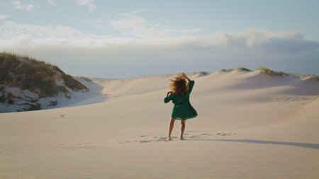 Silhouette passionate girl performing freestyle at desert dunes in distance. Young african american woman dancing emotionally wearing black dress at summer evening. Brunette moving body in wilderness.の写真素材