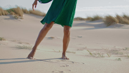 Woman slim legs dancing at sand desert summer day close up. Unknown african american girl drawing lines with feet on sandshore. Refined young dancer moving smoothly on wild beautiful nature.の写真素材