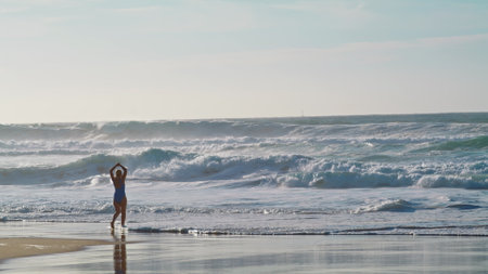 Silhouette going ocean waves on stormy day. Dangerous sea water rolling to beach splashing in sunny morning. Unknown person athlete relaxing meditating on seashore. Extreme seascape landscape concept.の写真素材