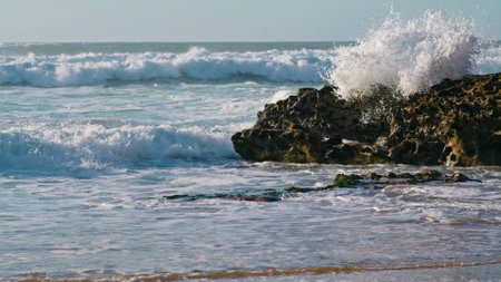 White waves crashing rocks in sunny morning. Storming ocean landscape view. Extreme foaming sea...