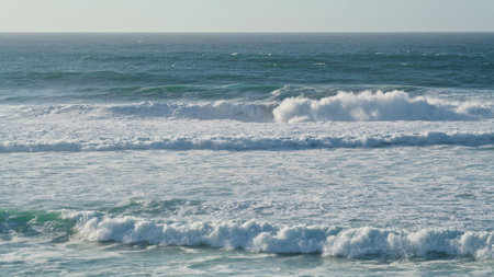 White sea waves rolling coastline on sunny morning. Storming ocean water foaming washing seashore in...