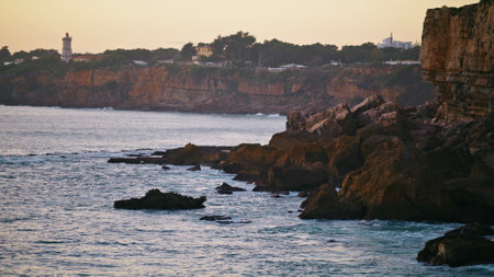 Morning rocky coastline landscape view. Tranquil travel island before sunrise. Calm ocean waves rippling washing cliff in peaceful evening. Idyllic seashore vacation scenery destination concept.の写真素材