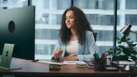 Young latin businesswoman have video conference sitting desk company office close up. Smiling woman manager talking with clients using online call. Technology in modern corporate business concept.の写真素材