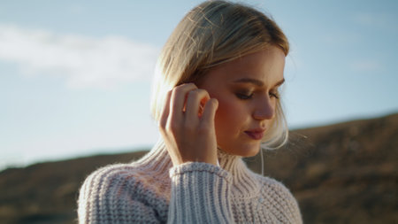 Walking girl wearing headphones nature background. Blonde lady crossing hilltop alone closeup....