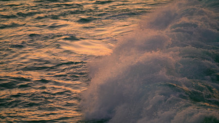 Dusk water breaking by marine rocks outdoors close up. Stormy ocean waves covering huge stone at...