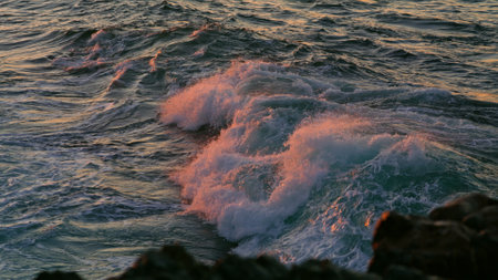 Powerful ocean waves foaming at sunrise nature close up. Breathtaking view water breaking over black rocks tropical shore. Sea streams splashing at summer morning. Scenic marine landscape conceptの写真素材