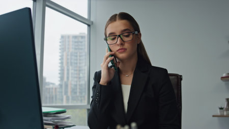 Beautiful businesswoman making call in business center. Focused assistant work making arrangements at contemporary workplace. Serious lawyer executive checking documents. Corporate manager specialist.の写真素材