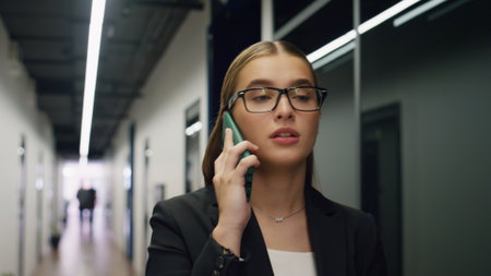 Confident manager speak smartphone corridor closeup. Beautiful ceo walk office talking with business partner. Attractive businesswoman discussing work consult client. Leadership professional concept.の写真素材