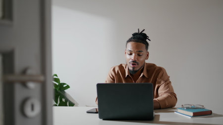 Friendly freelancer explaining laptop home closeup. African american man talking business partner on computer video chat alone. Gesturing businessman speaking online conference at domestic workplaceの写真素材