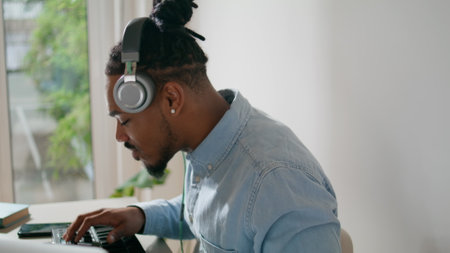 Focused dj playing music remotely closeup. African american headphones man working disc jockey midi...