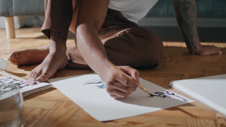 Young guy arms sketching paper at flat closeup. Modern man working on abstract painting. African american student drawing brush project design. Black hair artist sitting preparing fresh masterpieceの写真素材