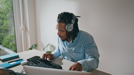 Dreadlocks man using console at table portrait. Sound producer creating music at home. Positive...