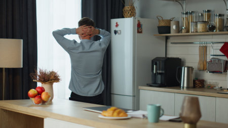 Stressed man freelancer failing work project walking on home kitchen feeling depressed. Back view of young frustrated guy worrying about job problems getting fired company losses. Businessman crisis.の写真素材