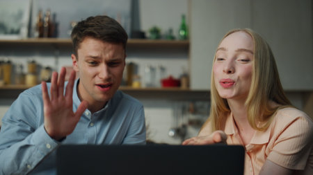 Cute smiling couple saying goodbye to friends on online meeting at home close up. Happy married pair...