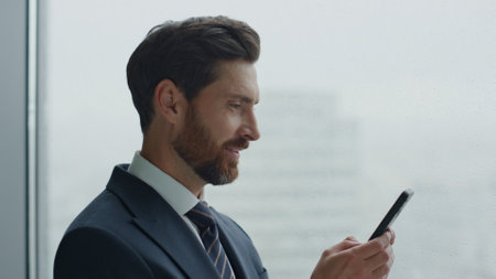 Attractive successful business man holding modern smartphone reading good news in message close up....
