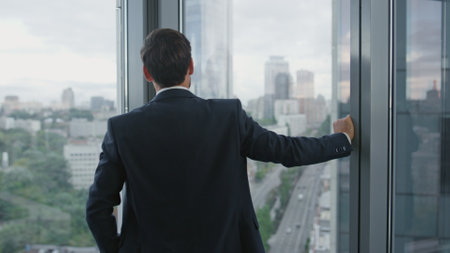 Serious bearded business man thinking about company strategy standing near panoramic window close up. Thoughtful manager crossing hands worrying about financial problems. Portrait of office worker.の写真素材