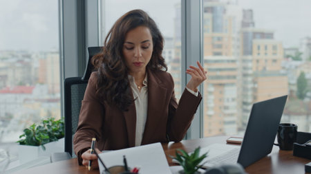 Confident woman manager reporting at video conference reading documents statistics close up. Smiling brunette businesswoman talking with partners on online meeting. Ceo lady speaking webcam in office.の写真素材