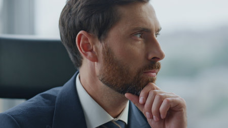 Focused entrepreneur thinking about business opportunity sitting office closeup. Portrait of serious bearded businessman worried company perspectives. Company man ceo working in cabinet wearing suit.の写真素材