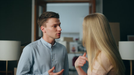 Angry couple discussing disagreement in unhappy relationship at home close up. Married young couple arguing feeling stress. Man woman taking offense on each other experiencing communication problem.の写真素材
