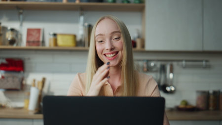 Excited happy woman laughing on web camera talking with friends close up. Attractive cheerful girl enjoying virtual meeting using video call at modern laptop. Smiling blonde communicating online.の写真素材