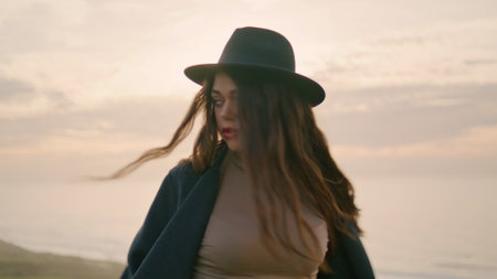 Carefree attractive girl spinning around relaxing on beautiful coast at autumn sunset close up....