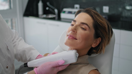 Hardware ultrasound correcting wrinkle making by unknown aesthetic specialist in cosmetology clinic close up. Attractive woman lying on facelift skin rejuvenation procedure. Non-surgical lifting.の写真素材