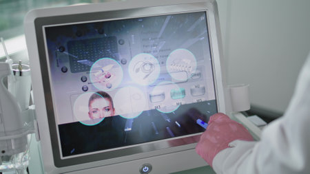 Unknown beautician touching cosmetology device screen choosing mode rejuvenation procedure closeup. Cosmetologist hand adjusting modern medical equipment preparing for laser treatment in beauty clinicの写真素材