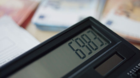 Closeup view of calculator display with calculations indoors. Numbers appearing on screen calculating device. Unknown person using calculator to counting. Accounting finance economy budget concept.の写真素材