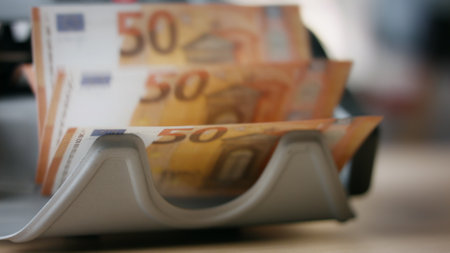 Automatic equipment counting euro bills denomination of fifty close up indoors. Pack of european currency calculating by modern bank device standing on table. Electronic counter for money operations.の写真素材