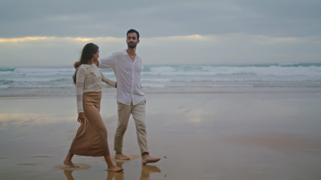 Loving couple going evening sea shore wide shot. Affectionate woman bonding man on dark sky beach. Married people embracing ocean horizon. Love sweethearts enjoying romantic date. Feelings conceptの写真素材