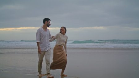 Happy sweethearts walking evening beach outdoors. Hispanic couple enjoying ocean coast outside. Two romantic lovers running on nature date. Smiling spouses spending time together. Leisure conceptの写真素材