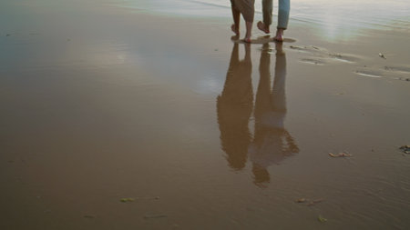Lovers feet walking sand beach at sea vacation. Unrecognizable couple stepping on shore outdoors. Closeup sweethearts legs celebrating anniversary vacation at marine nature. Relax recreation conceptの写真素材
