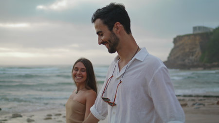 Carefree lovers walking on sandy beach closeup. Smiling girl relaxing with positive guy on beautiful summer nature. Affectionate couple looking each other enjoying tender moment together on seacoastの写真素材