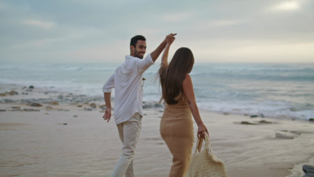 Love couple running ocean beach together closeup. Two people walking water shore outside. Ethnic spouses laughing on romantic date outdoors. Smiling adults going out sea coast. Nature leisure conceptの写真素材