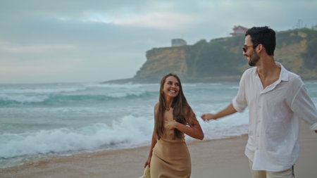Playful pair rejoicing ocean closeup. Positive lovers holding hands on evening sea coast. Romantic partners enjoying date on cloudy sky nature. Two loving people spend time together. Leisure conceptの写真素材