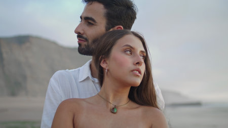 Sensual sweethearts hugging at seashore closeup. Sexy woman face looking camera portrait. Pair embracing at water view. Ethnic lovers enjoy sandy beach romantic date. Couple bonding at ocean landscapeの写真素材