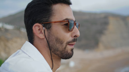 Cheerful man model enjoy beach on sea landscape closeup. Sunglasses tourist watching water shore portrait. Ethnic guy smiling looking nature outdoors. Sexy male delighting ocean. Leisure conceptの写真素材