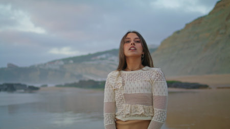 Sexy woman moving sensually on summer seashore closeup. Laughing model posing evening seaside portrait. Energetic lady enjoying sunset at cloudy ocean side. Sea waves washing shore. Lifestyle conceptの写真素材