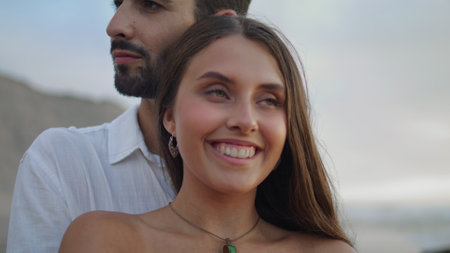 Laughing woman enjoying anniversary vacation portrait. Bonding couple relaxing at sea beach nature. Ethnic lovers hugging at family trip. Smiling lady looking camera. Romantic date together conceptの写真素材