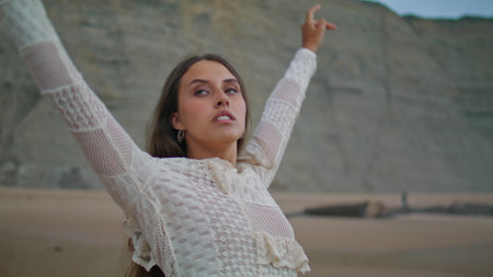 Romantic lady relaxing evening seashore. Sexy woman raising hands to sky stretching body at summer vacation. Female person meditating at sandy beach. Tranquility and connect with nature conceptの写真素材