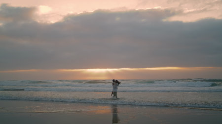 Beautiful pair spinning morning sea beach. Happy people rejoicing together at cloudy nature. Romantic lovers embracing each other at ocean waves. Cheerful couple celebrate honeymoon sunrise horizonの写真素材