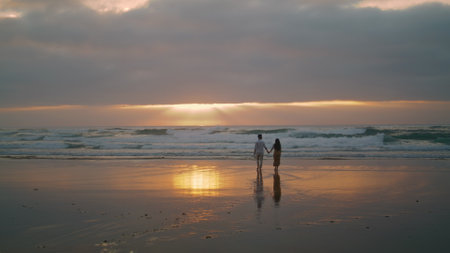 Sweethearts silhouettes walking sunbeams sea landscapes. Affectionate people enjoying romantic date evening nature. Loving tourists relaxing on honeymoon vacation. Spouses celebrating on ocean coastの写真素材