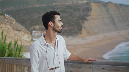 Peaceful guy enjoying sea horizon closeup. Calm person walking stairs watching sunny nature and morning ocean. Rest man going stairway up looking at marine landscape. Positive tourist travelling aloneの写真素材