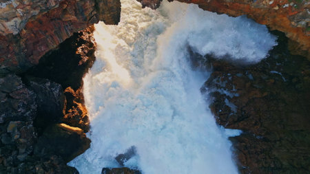 Aerial huge waves crashing on rocky shore super slow motion. Breathtaking view foamy ocean water breaking on volcanic stones seashore. Dangerous sea surf splashing on rough cliffs. Marine scenery.の写真素材