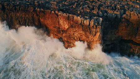 Huge ocean splashes crashing high dangerous rocks seacoast in super slow motion. Aerial view powerful waves hitting high coastal cliffs making white foam. Breathtaking rough sea splashing on stones.の写真素材